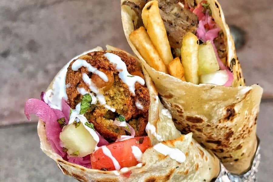 Un primer plano de dos wraps con falafel y papas fritas sobre una mesa.