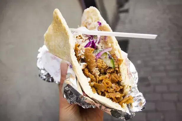 Una persona sostiene un sándwich de pita con un tenedor dentro.