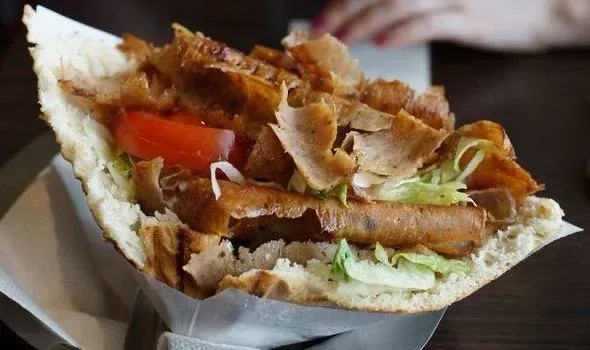 Un primer plano de un sándwich con carne y verduras sobre una mesa.