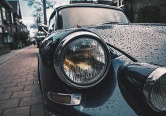 Eine Nahaufnahme des Scheinwerfers eines Autos auf einer gepflasterten Straße.