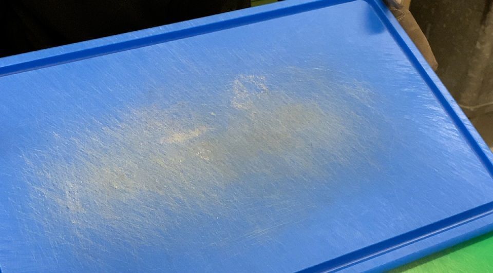 Blaues Schneidebrett mit Messerspuren.