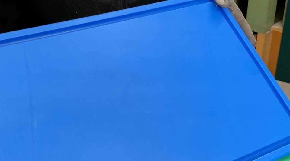 Blaues Kunststofftablett wird angehoben, wodurch die Kanten und die Form des Tabletts sichtbar werden.