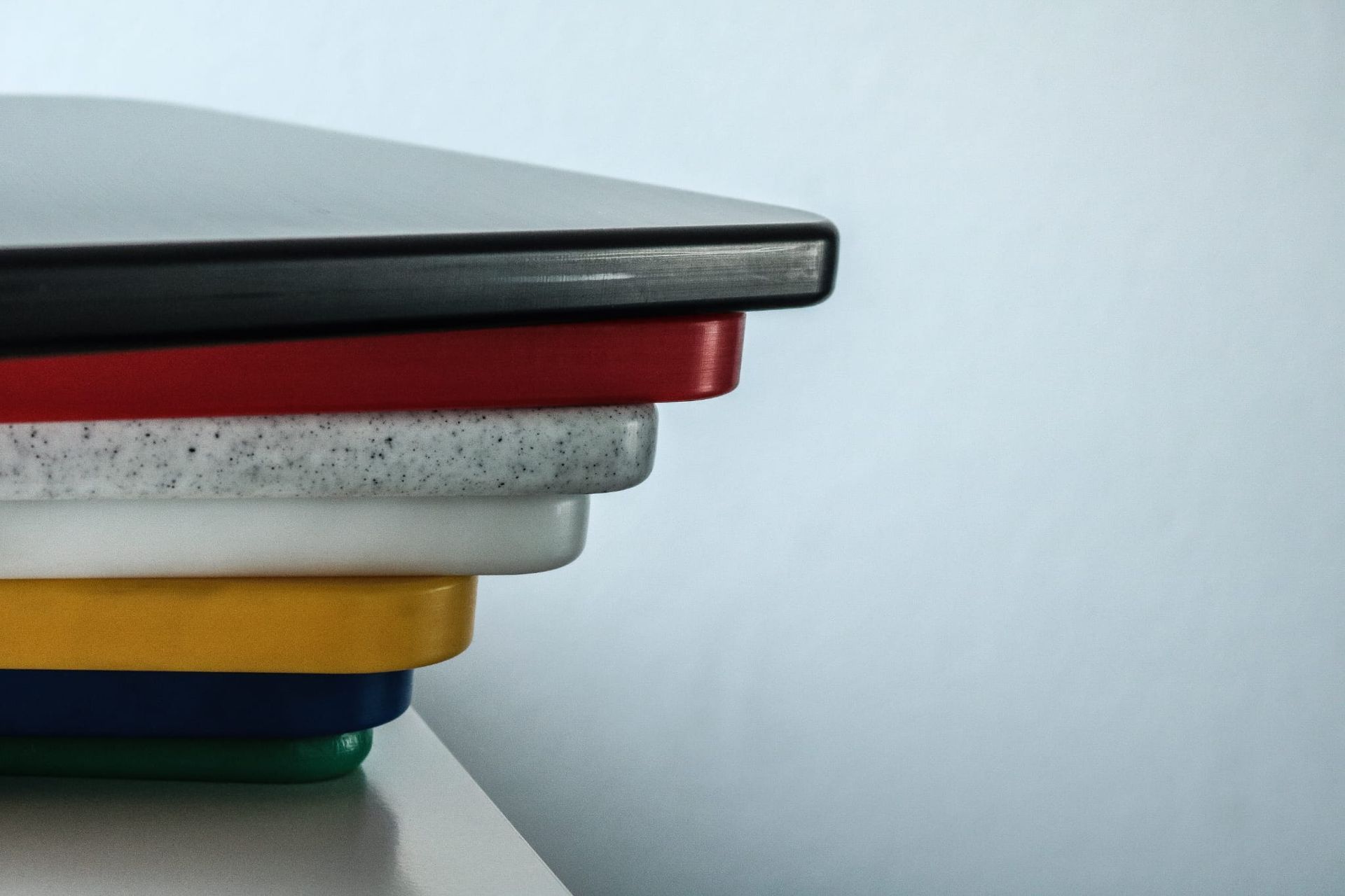 Stapel bunter rechteckiger Schneidebretter auf einer Glasoberfläche.