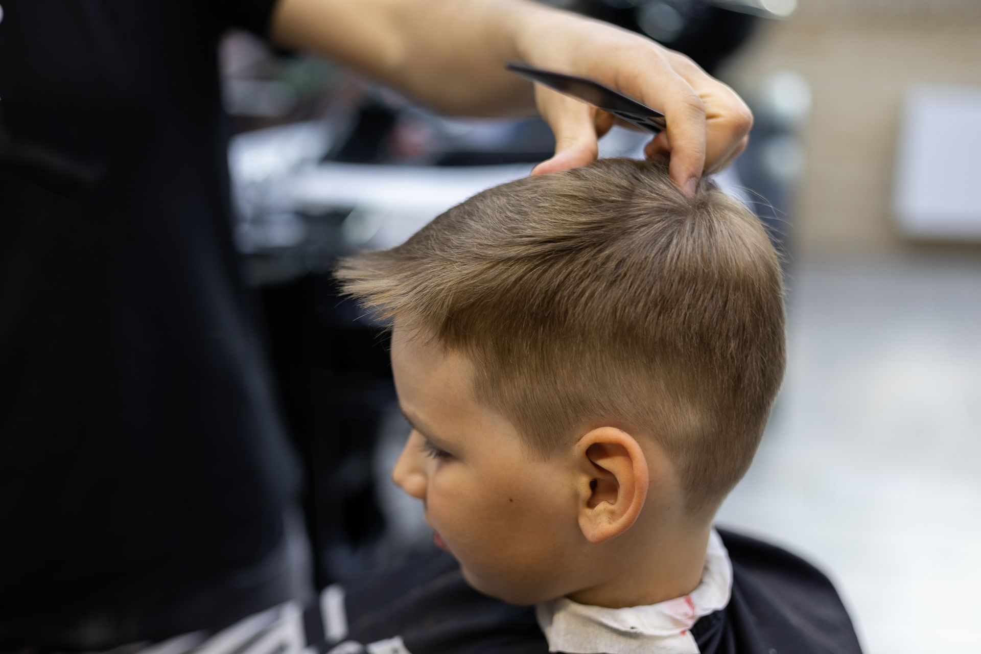 Un coiffeur coupe les cheveux d'un enfant dans un salon.