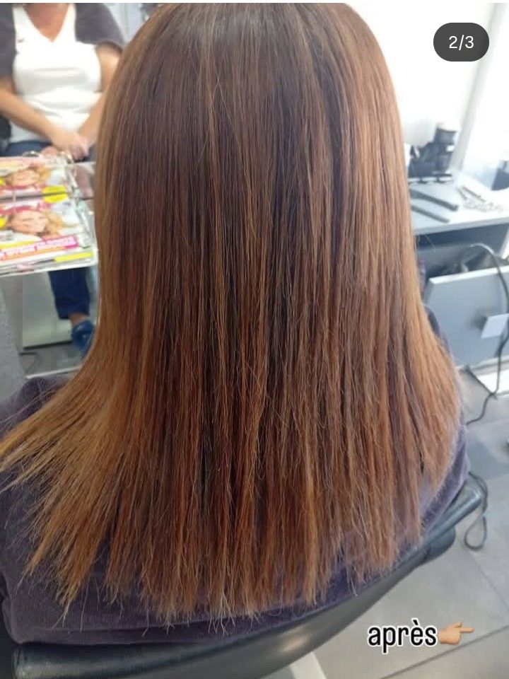 Cheveux bruns, mi-longs, lissés. Ambiance salon de coiffure. 