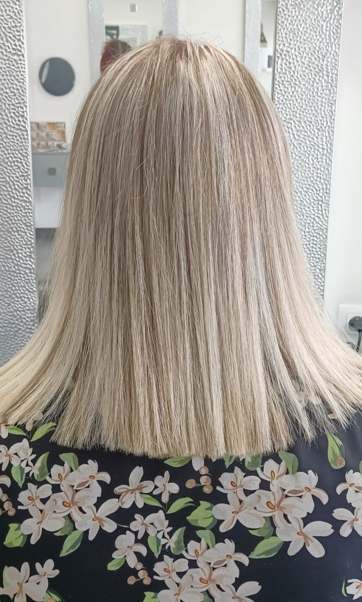 Cheveux blonds lissés et texturés, sur un haut à motifs floraux.