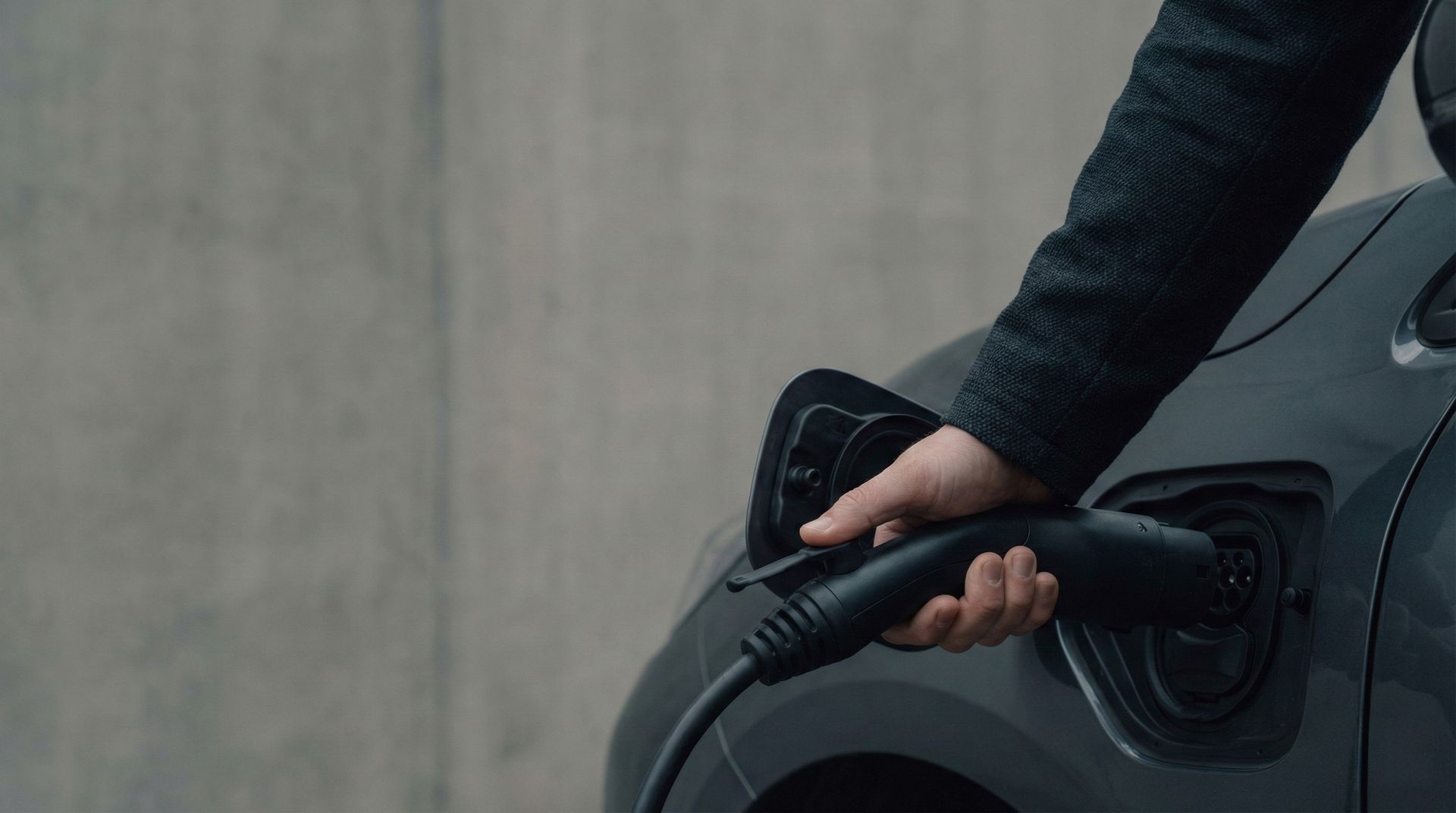Une personne branche un câble de recharge pour véhicule électrique à une voiture.