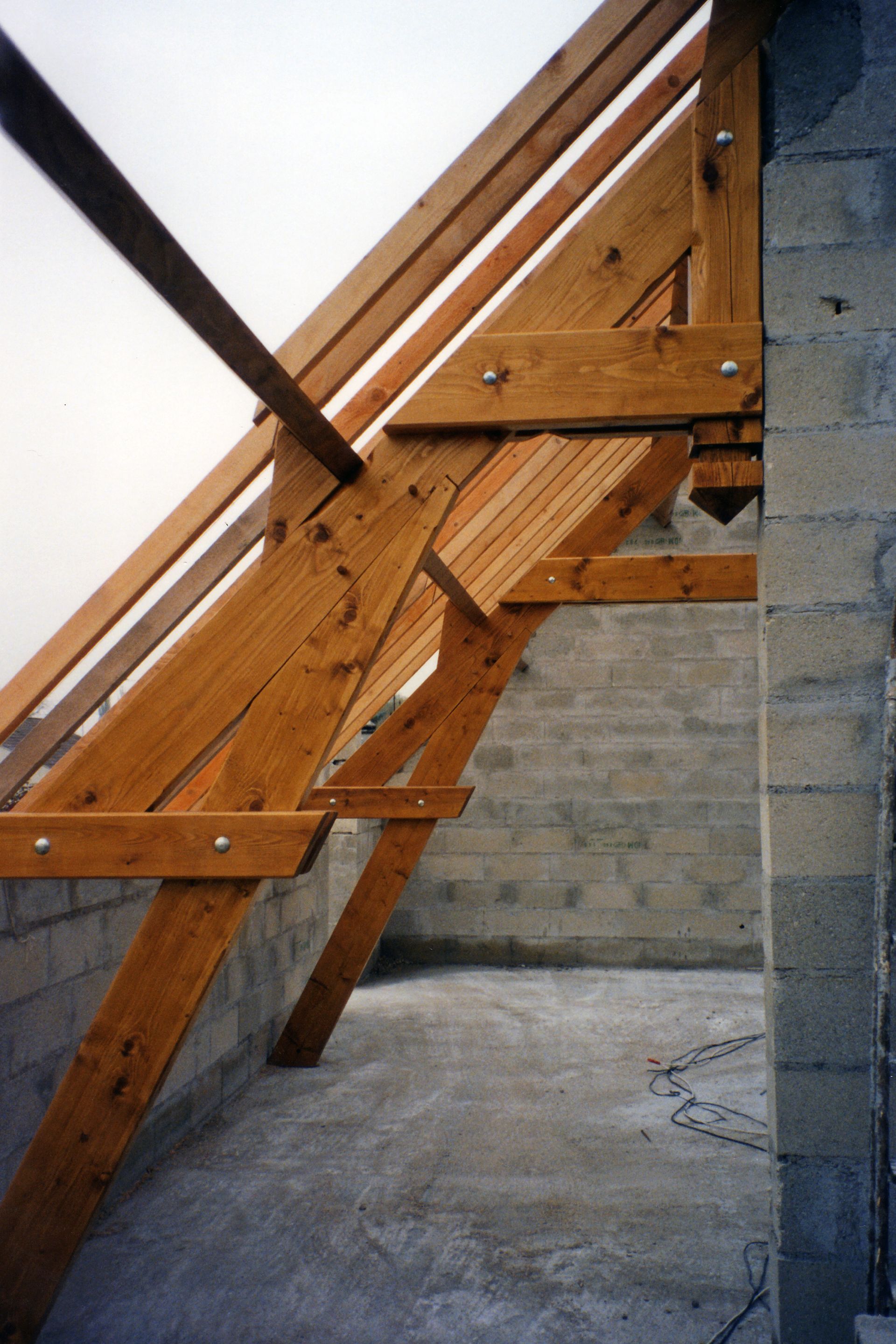 Structure de charpente en bois, le long d'un mur en parpaings