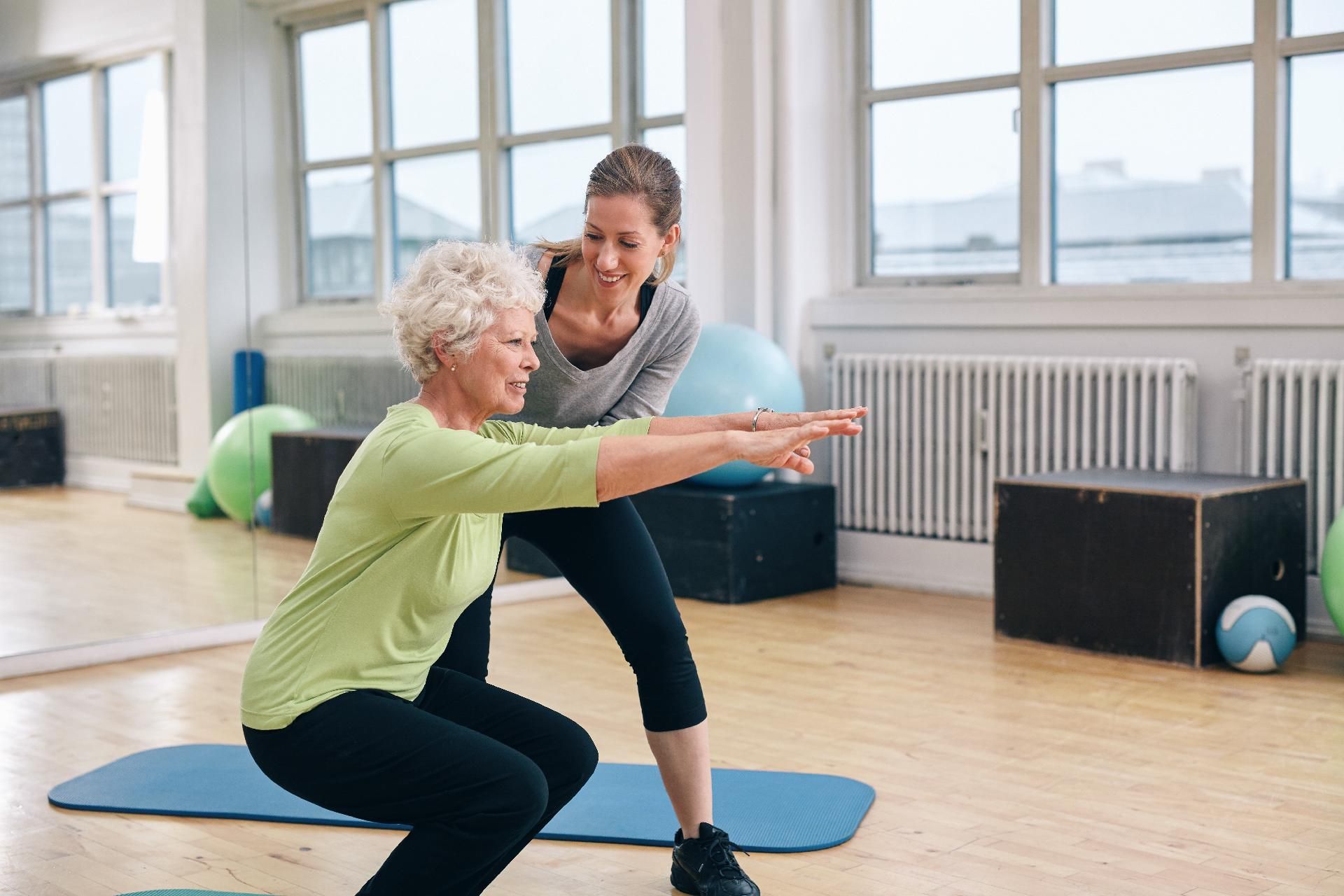 Ältere Frau macht Übungen mit ihrem Personal Trainer