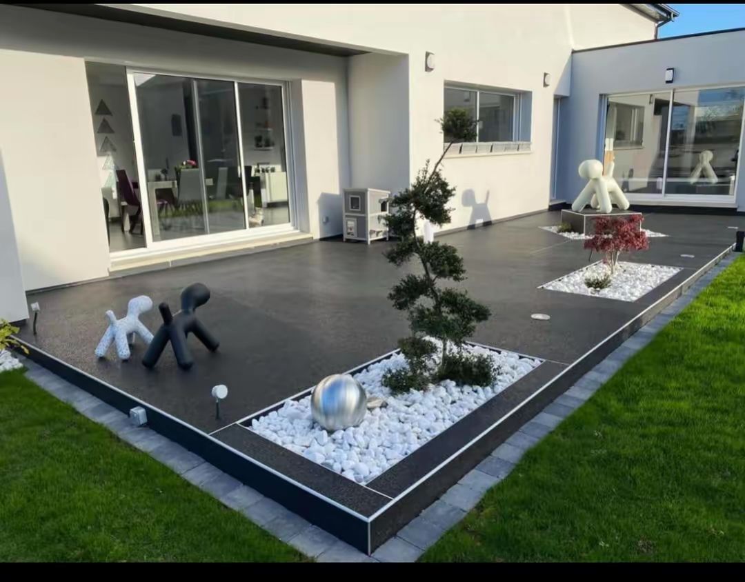 Terrasse moderne dans un jardin avec terrasse en bois gris foncé, touches de blanc et sculptures décoratives de chiens.