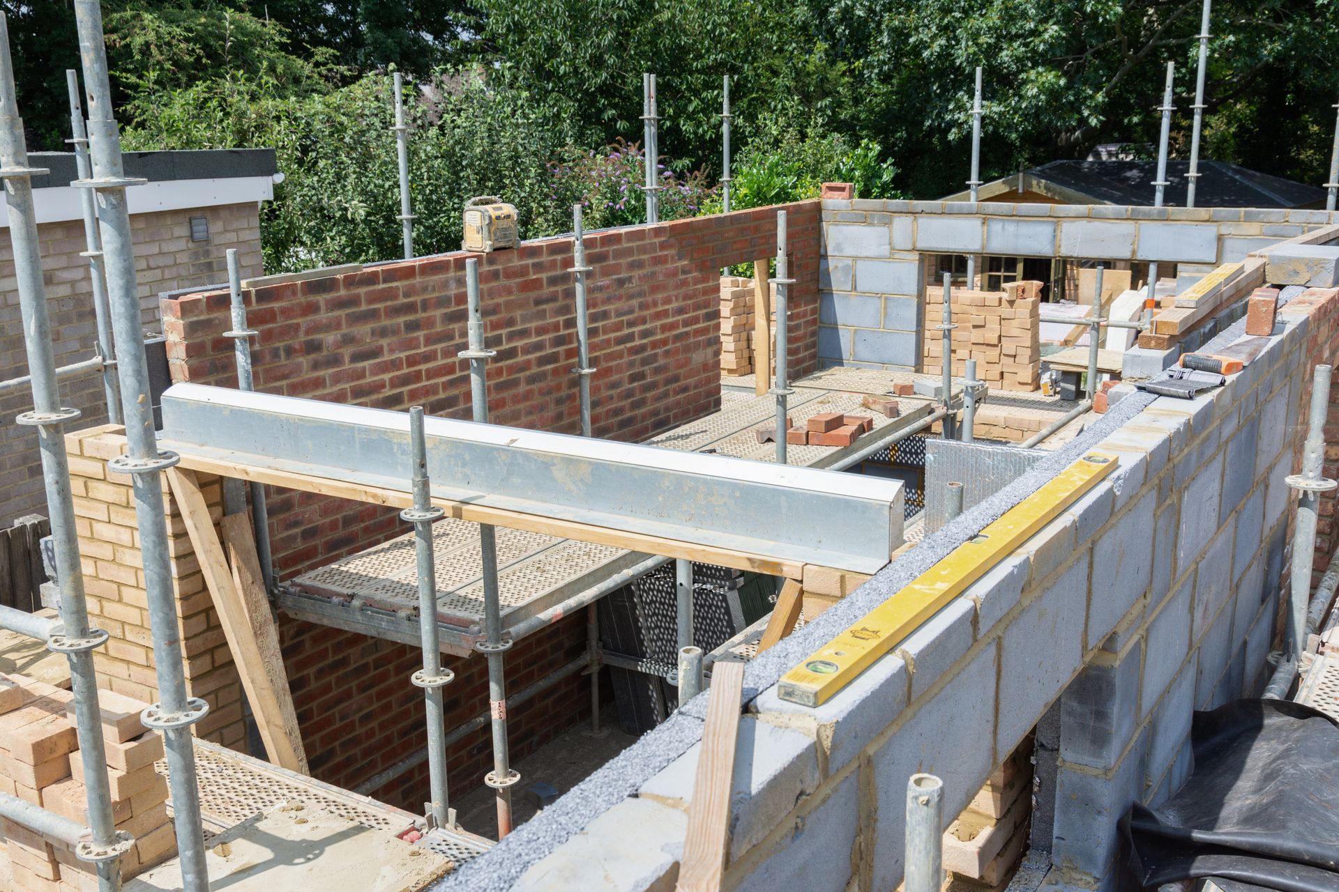 Chantier de construction : construction de murs en briques et en parpaings avec échafaudages, poutre d'acier en place.