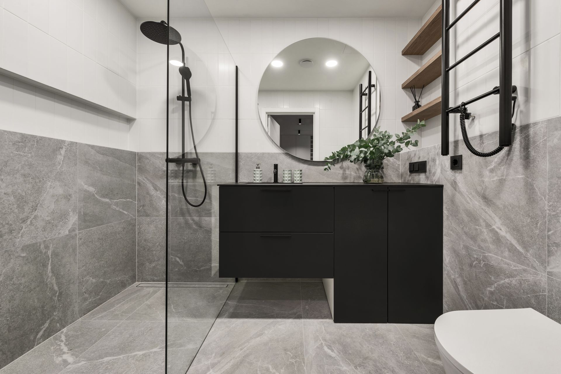 Salle de bains moderne avec carrelage gris et blanc, meuble-lavabo noir et douche à l'italienne.