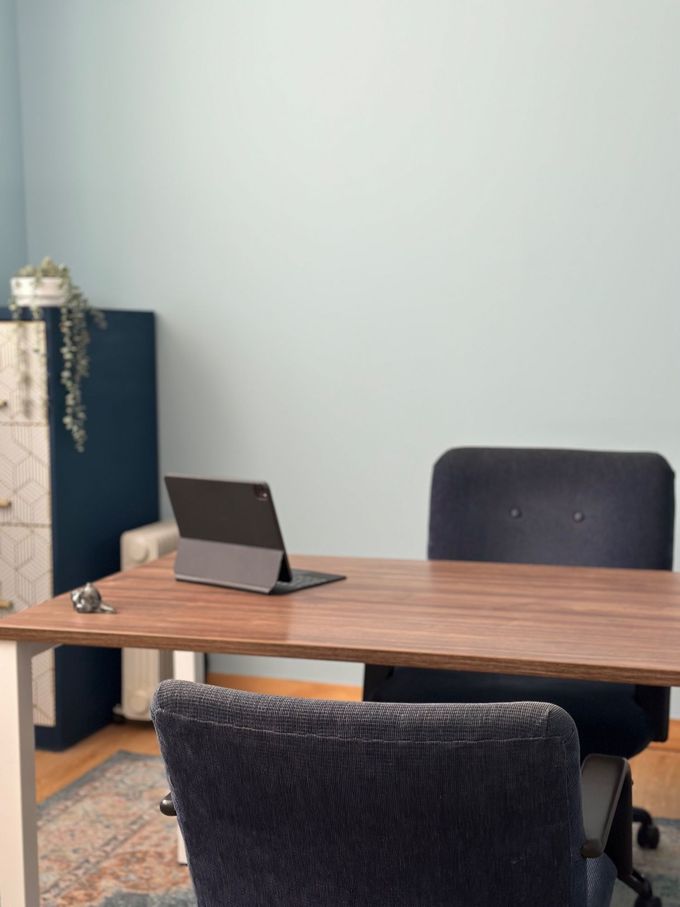 Escritorio de oficina moderno con un portátil, una silla y una planta pequeña frente a una pared clara