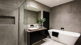 Salle de bains grise moderne avec baignoire blanche, vanité et douche.