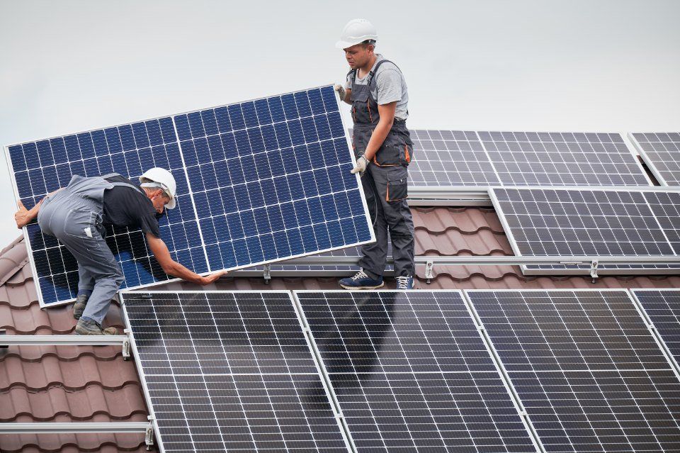Two fitters install solar panels on the roof of a house