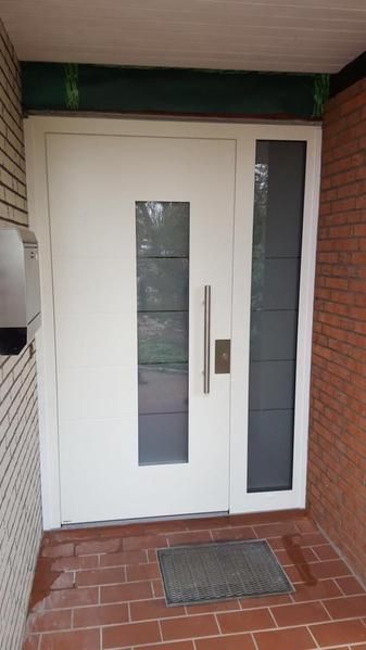 Eine weiße Tür mit einer Ziegelwand und einer Matte davor.