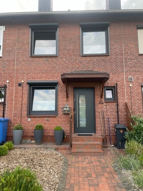 Ein Backsteinhaus mit einer schwarzen Tür und Fenstern