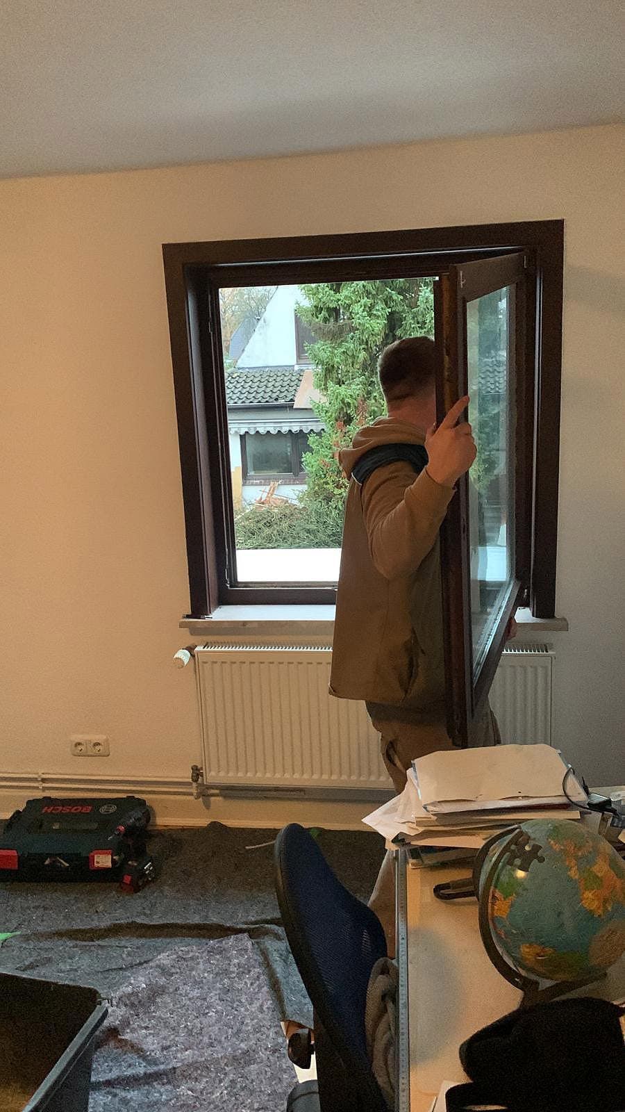 Ein Mann steht vor einem Fenster in einem Wohnzimmer.
