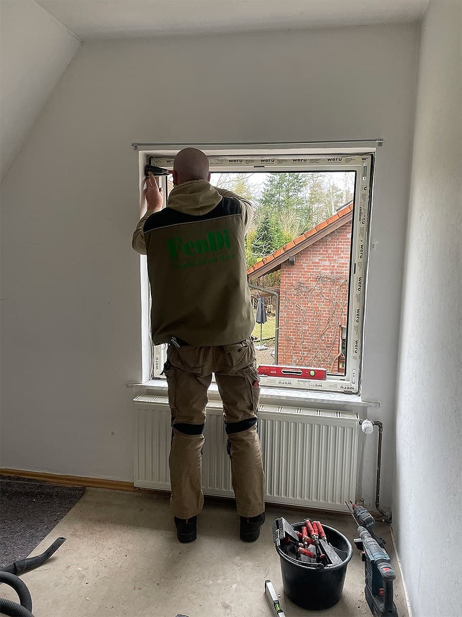 Ein Mann steht in einem Zimmer vor einem Fenster.