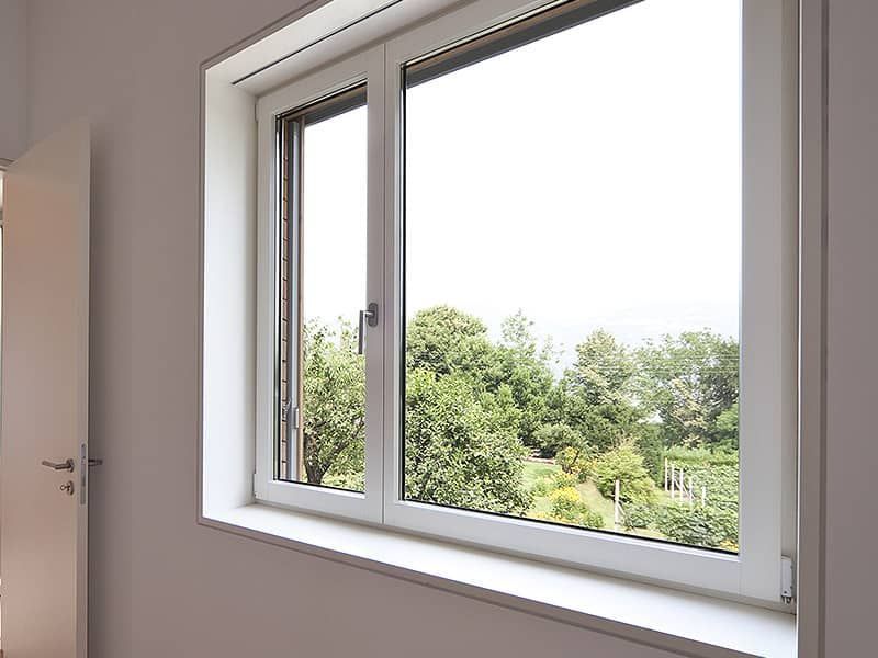 Ein weißes Fenster mit Blick auf Bäume in einem Zimmer.