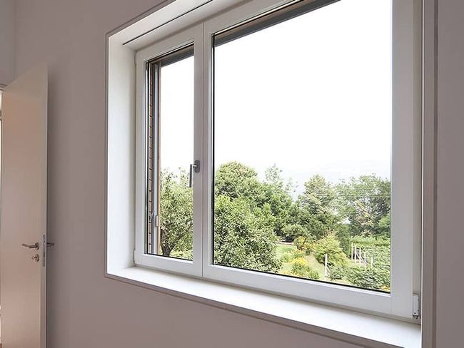 Ein weißes Fenster mit Blick auf Bäume in einem Zimmer.