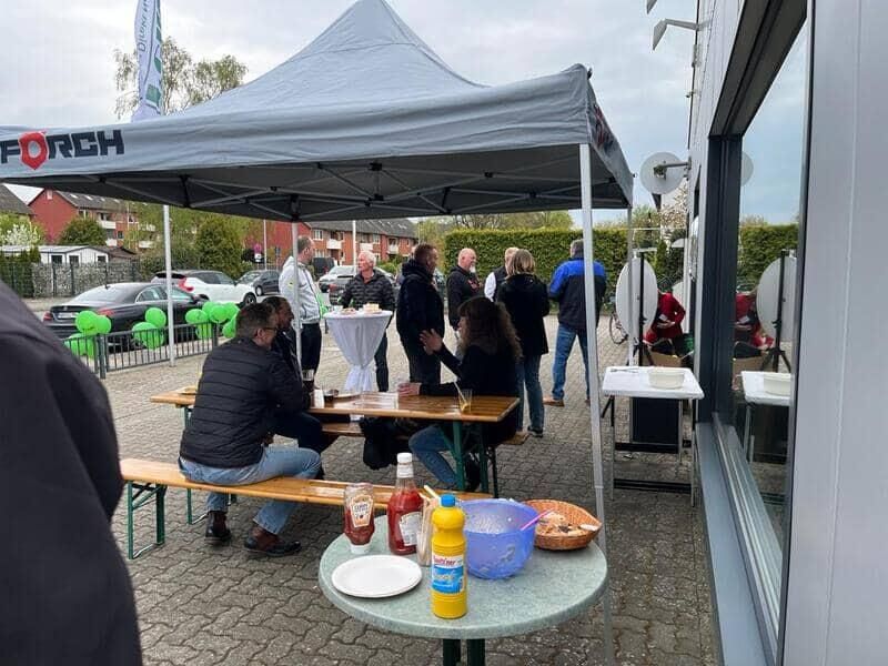 Eine Gruppe von Leuten sitzt an Tischen unter einem Zelt.