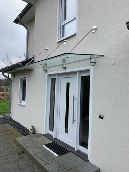 Ein weißes Haus mit einem Glasdach über der Tür