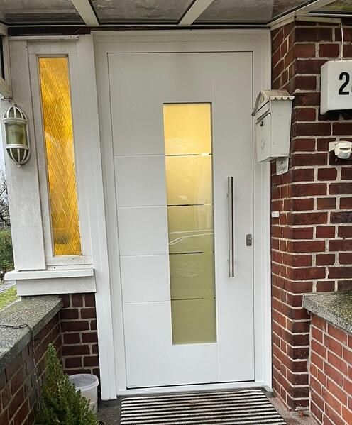 Die Haustür eines Backsteinhauses mit einer weißen Tür und einem Fenster.