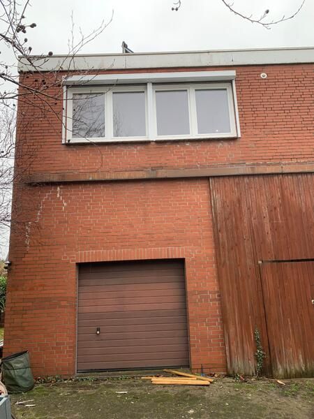 Ein Backsteingebäude mit einem Garagentor und einem Fenster.