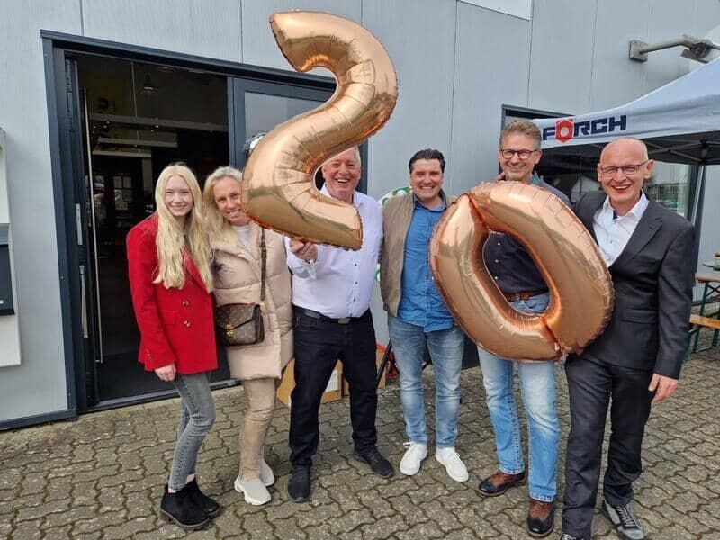 Eine Gruppe von Menschen hält Luftballons in Form der Zahl 20.