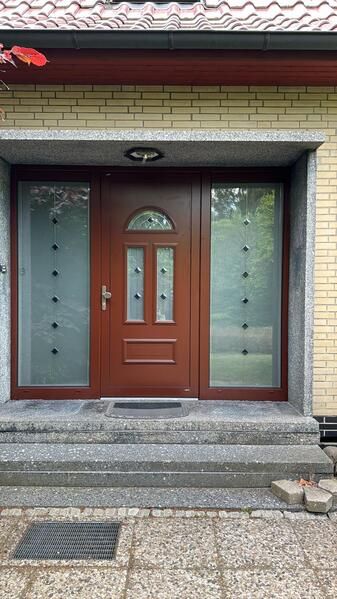 Die Haustür eines Hauses mit Treppe und Holztür.