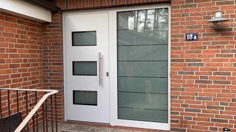 Vor einem Backsteingebäude befindet sich eine weiße Tür.