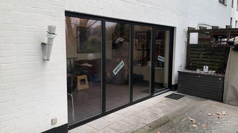 Ein weißes Backsteingebäude mit einer großen Glasschiebetür, die auf eine Terrasse führt.