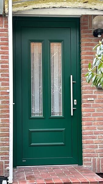 Eine grüne Haustür steht auf einer Backsteinmauer.