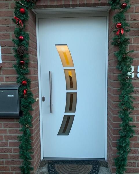 Eine weiße Tür an einer Ziegelwand, die weihnachtlich dekoriert ist