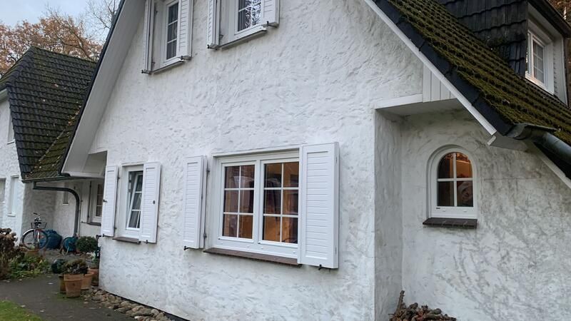 Ein weißes Haus mit schwarzem Dach und weißen Fensterläden.