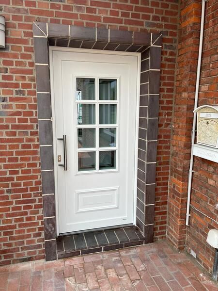 Eine weiße Tür befindet sich an einer Backsteinmauer neben einem Briefkasten.