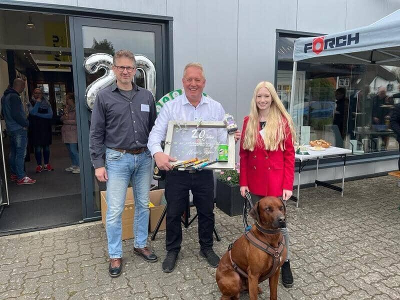 Eine Gruppe von Menschen steht neben einem Hund vor einem Gebäude.