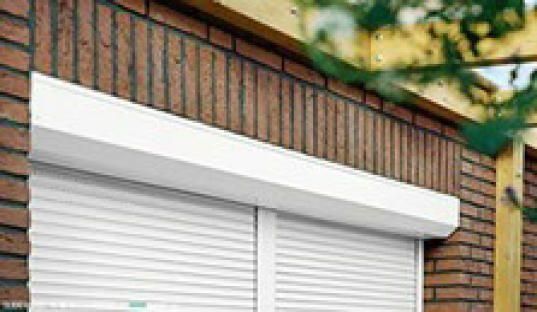 An einer Ziegelwand hängt ein weißer Rollladen.