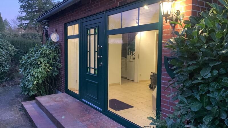 Ein Haus mit einer grünen Tür und vielen Fenstern ist nachts beleuchtet.