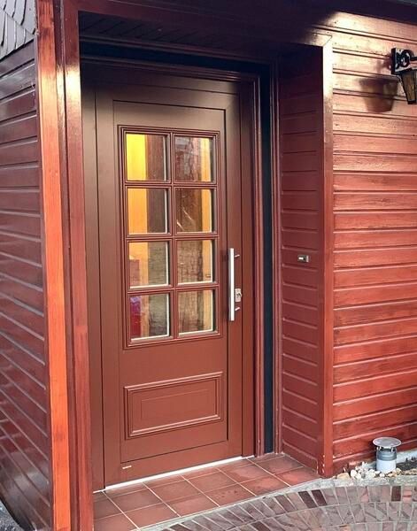 Eine braune Tür mit einem gemauerten Gehweg davor