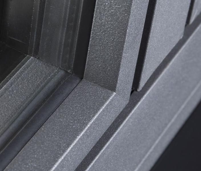 Eine Nahaufnahme eines grauen Fensters mit einem schwarzen Rahmen auf schwarzem Hintergrund.