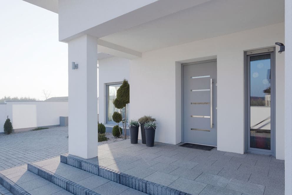 Ein weißes Haus mit einer grauen Haustür und einer Treppe, die dorthin führt.