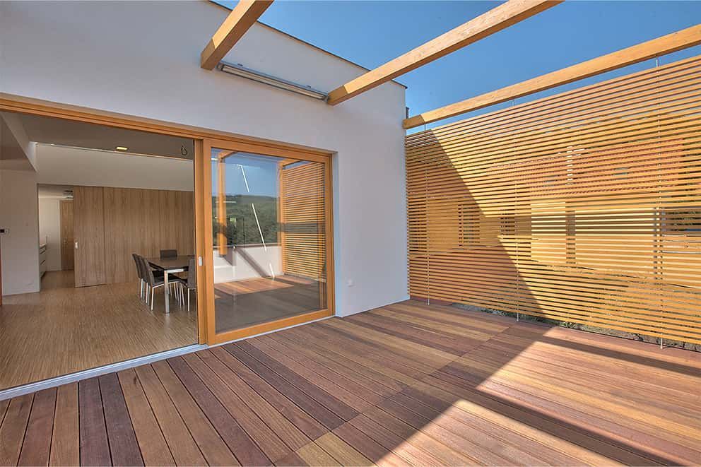 Ein Haus mit einer Holzterrasse und Glasschiebetüren