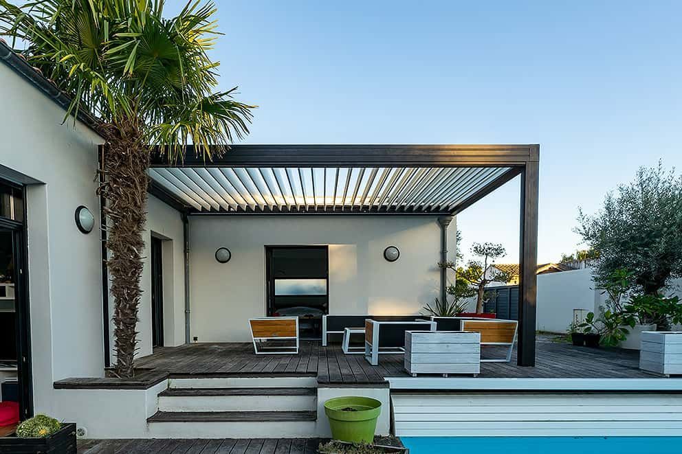 Ein Haus mit einem Swimmingpool und einer Pergola darüber.