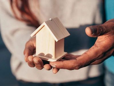 Una persona sostiene una pequeña casa de madera en sus manos.
