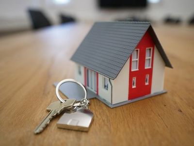 Una casa modelo y llaves sobre una mesa de madera