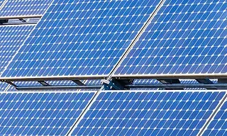 Primer plano de paneles solares azules dispuestos en una cuadrícula, capturando la luz solar para la conversión de energía.