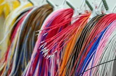 Primer plano de una serie de cables eléctricos de colores. Son rojos, naranjas, azules, blancos, marrones y rosas, y parecen estar perfectamente ordenados.