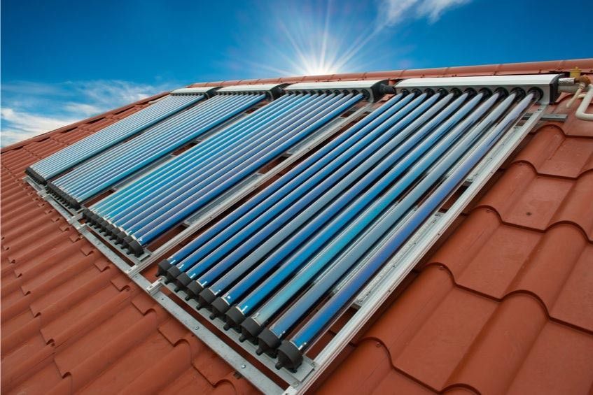 Una fila de paneles solares en un techo con el sol brillando a través de ellos.